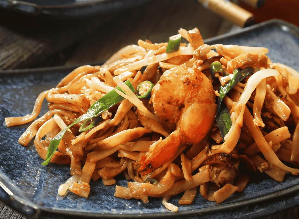 Freshly stir-fried char kway teow with prawns and bean sprouts in a wok